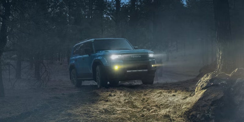 2027 Toyota Land Cruiser driving across a dirt trail with Full-Time 4WD