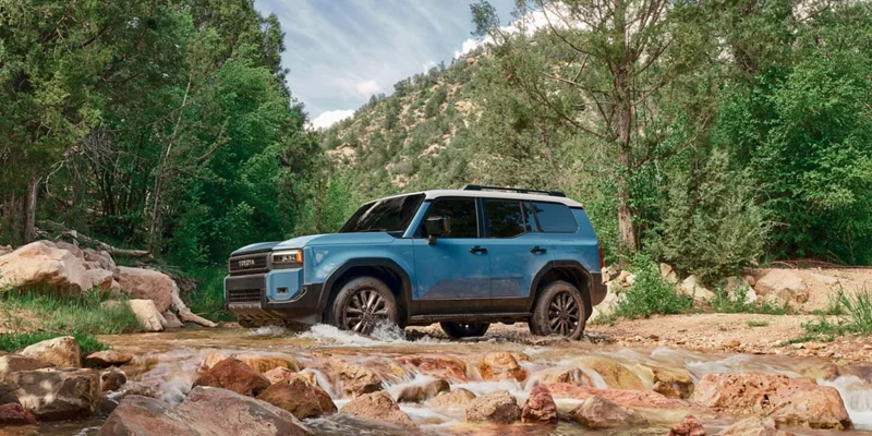 2027 Toyota Land Cruiser climbing an off-road trail with 8.7 inches of ground clearance